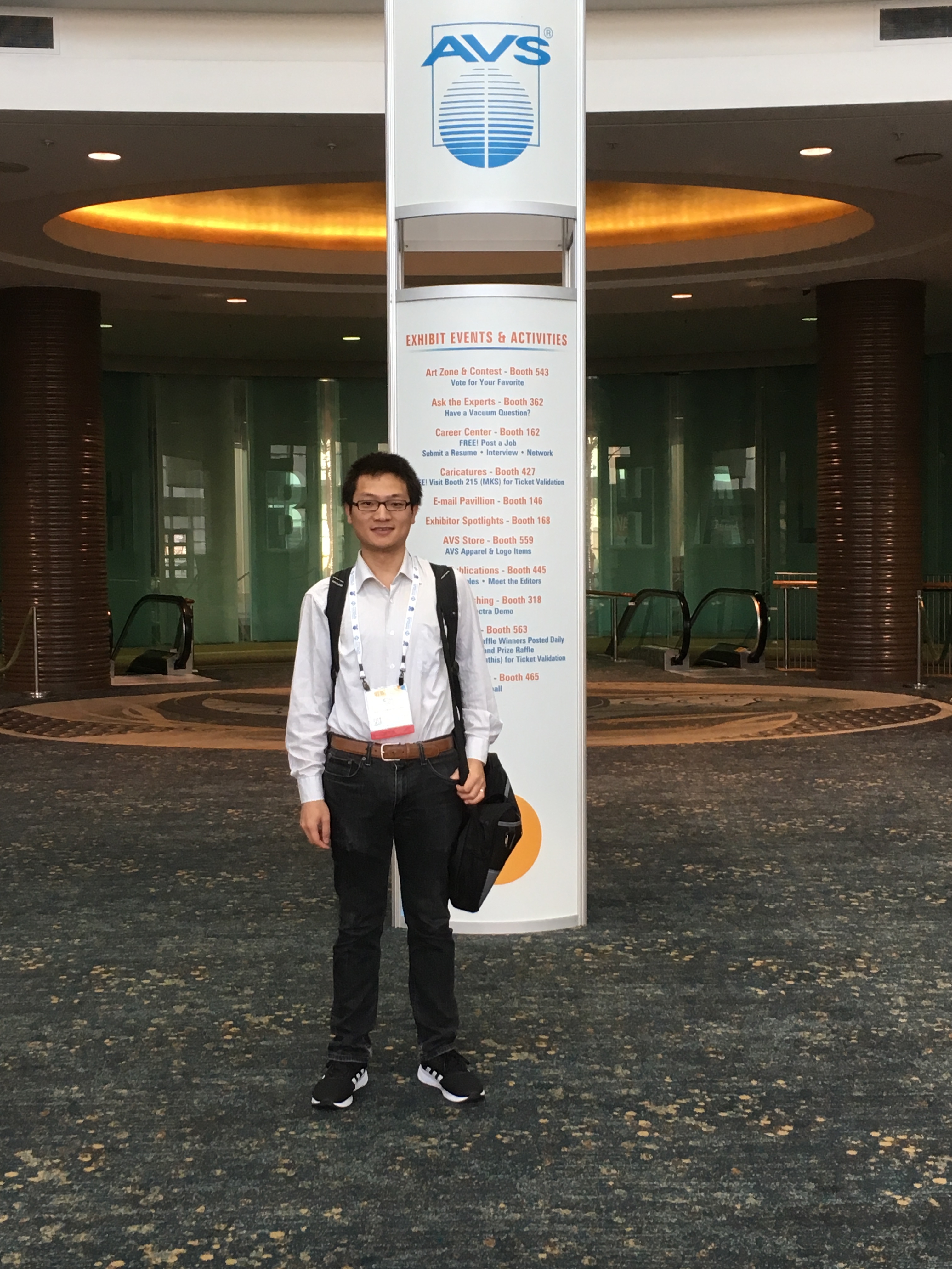 Qing poses near the schedule for the AVS symposium.